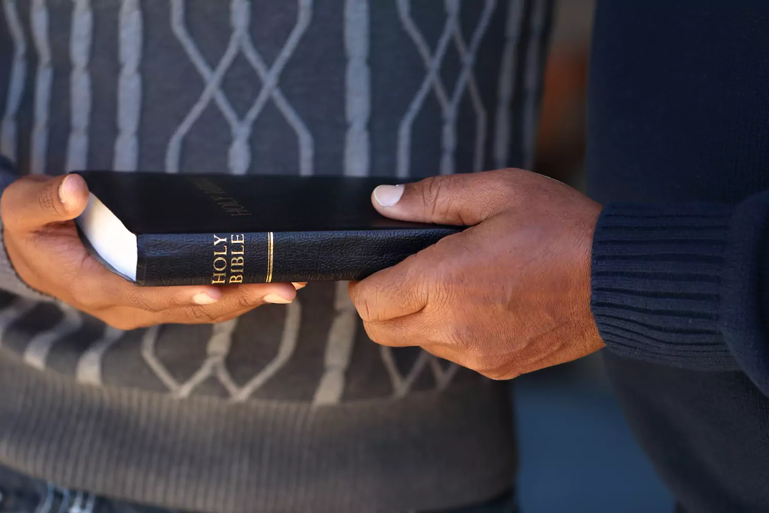 An older man passes a bible on to a younger man.