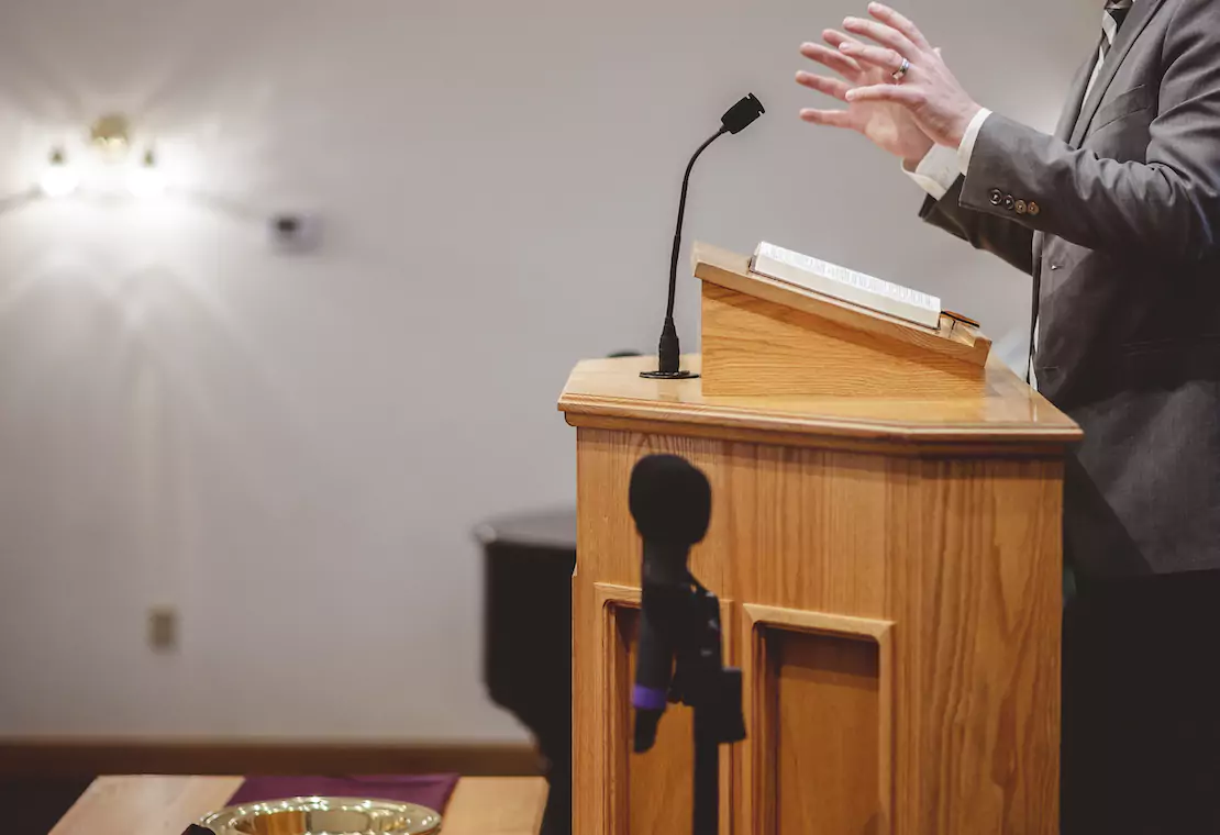 Man preaching with Bible on pulpit in front of him