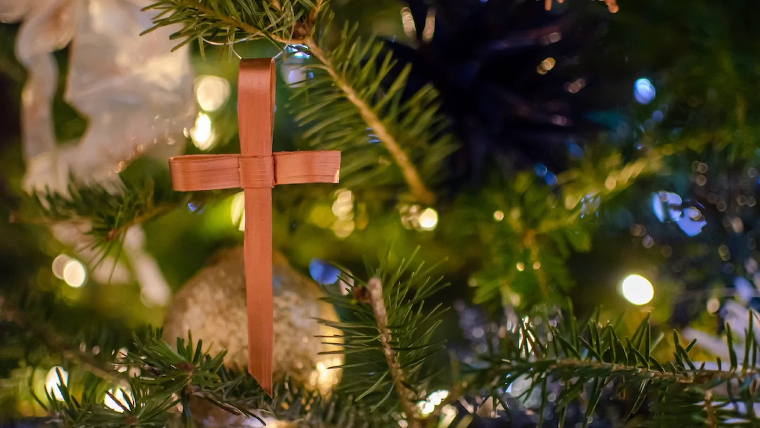 close-up of a homemade cross ornament on a traditional Christmas tree