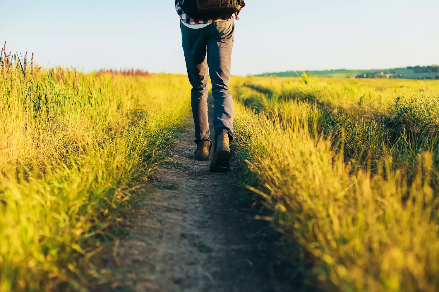 back view of a pastor walking down a grassy lane in boots as he ponders the idea of self-esteem in his ministry