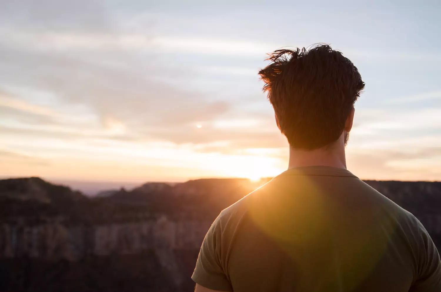 a young man stares off into the sunset in the distance thinking about knowing God, not just knowing about him.