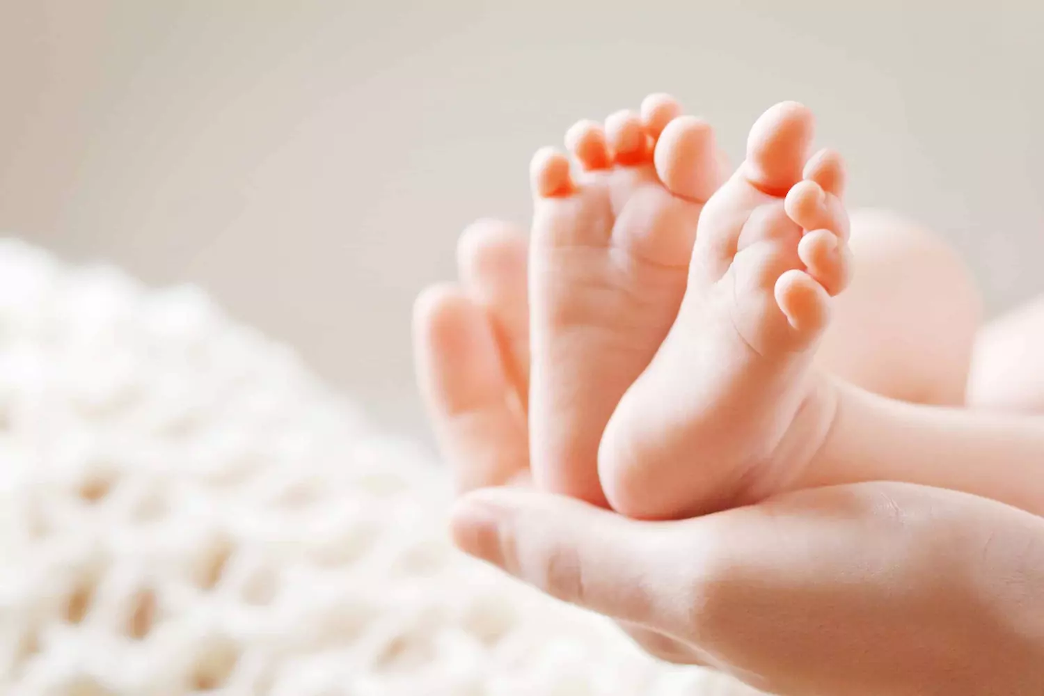 A mother hold's her baby's feet in her hands.