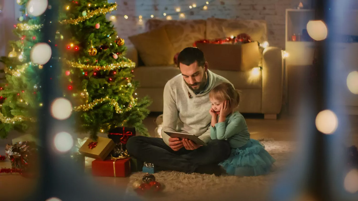 A weary pastor sits with his daughter by the Christmas tree, enjoying rest during the busy holiday season.