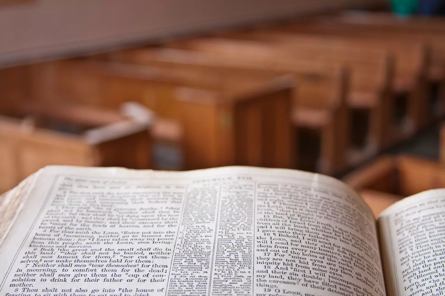 An open Bible sits on a pulpit at the front of a church, pews in the background, symbolizing preaching that contains sermon illustrations that connect with the audience.