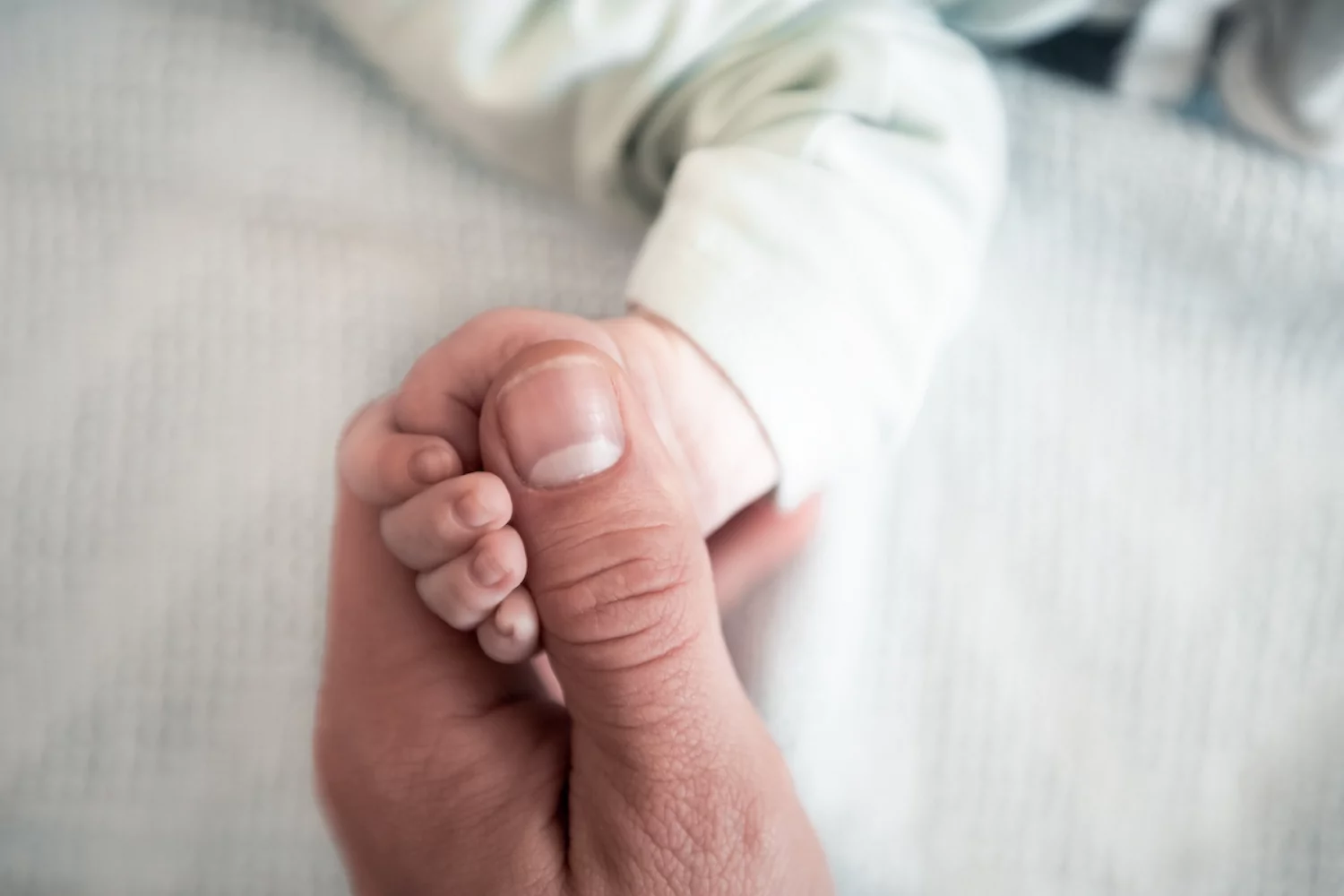 A man holds his baby's hand.