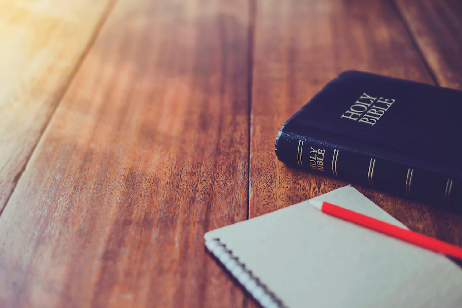 A Bible and notebook on a wooden table for writing pastoral resolutions.